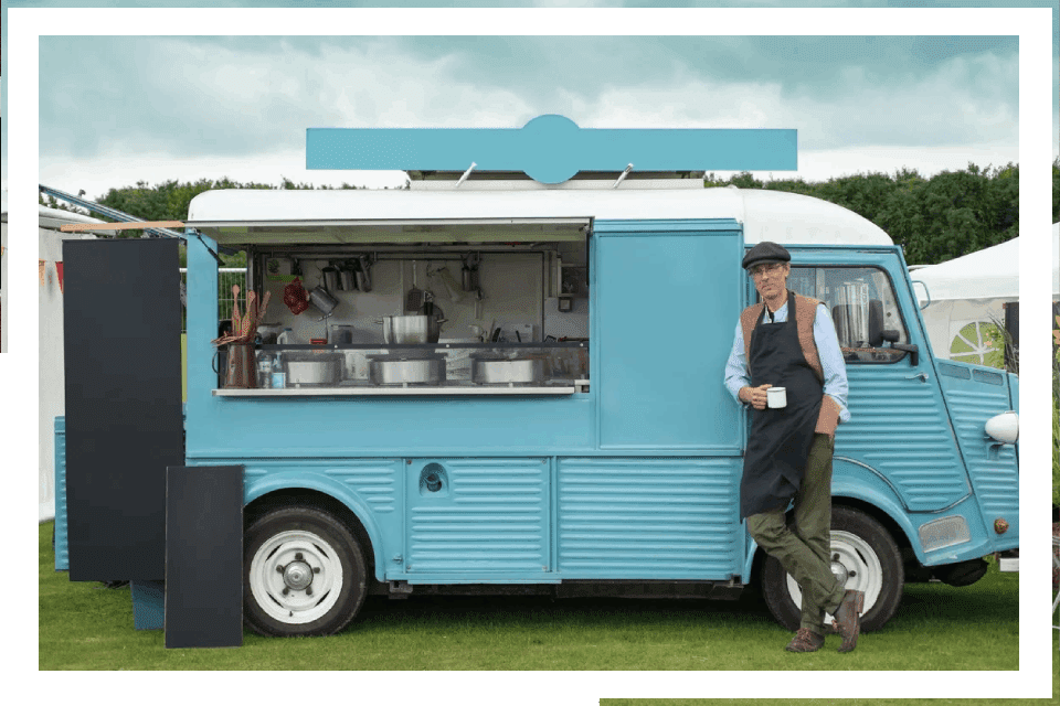 Man serving food from vintage blue van.
