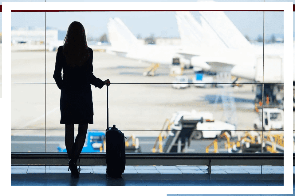 Woman waiting at airport with luggage.