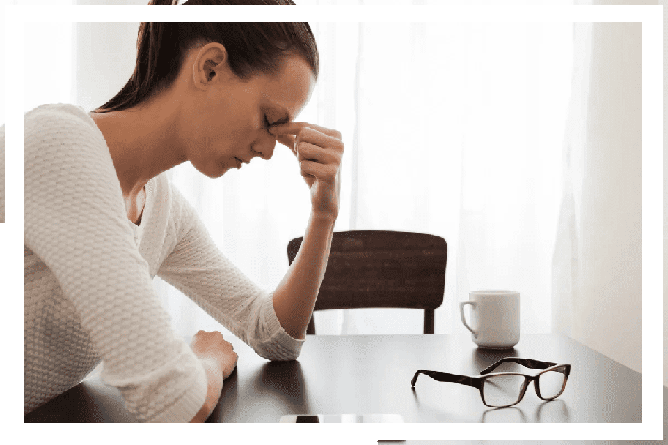 Woman stressed at desk, head in hands.